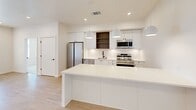 This modern single-floor residence in Oklahoma City offers three bedrooms and two bathrooms within a thoughtfully designed layout. The contemporary kitchen is a standout feature, equipped with stainless steel appliances — including a refrigerator, range, microwave, and dishwasher — set against crisp white cabinetry accented by warm wood open shelving. A large white peninsula island anchors the space, illuminated by stylish pendant lights, while light hardwood flooring adds warmth throughout the main living areas. The hallway connects the living space to the bedrooms, with clean recessed lighting and light hardwood floors maintaining a cohesive, modern aesthetic. The bedrooms are carpeted for comfort, with ceiling fans and windows that invite natural light and outdoor views. The primary bedroom includes access to a dedicated walk-in closet featuring built-in shelving and hanging rods for generous storage. The primary bathroom is finished with slate-toned tile flooring, a glass-enclosed walk-in shower with matte black fixtures, and a bold navy vanity. The secondary bathroom features tile flooring and a tub-shower combination. An additional walk-in closet with multi-level shelving provides ample storage. The overall design is clean, bright, and cohesive throughout.