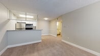 Located at 6158 Beacon Isles Dr in Town N' Country, Florida, this single-floor residence offers a clean, modern aesthetic throughout its thoughtfully designed layout. The open-concept living and dining area is finished with neutral-toned carpet and soft beige walls, creating a bright and welcoming atmosphere. A textured ceiling adds subtle architectural character throughout the space.

The kitchen is equipped with stainless steel appliances, including a refrigerator, range, and over-the-range microwave. White cabinetry pairs with granite-style countertops, and a peninsula with a built-in sink serves as a functional divider between the kitchen and the living area. Light wood-look flooring runs through the kitchen, providing a clean contrast to the carpeted areas.

The bedroom is generously proportioned, featuring plush carpet, neutral walls, and a window with blinds that allows for natural light. A dedicated closet with built-in rods provides convenient storage. An additional room near the entry offers flexibility as a secondary bedroom or office, also carpeted and bathed in natural light from a large window.

The bathroom is neatly appointed with white cabinetry, a granite-topped vanity, wood-look flooring, and a tub-shower combination. The overall design of this residence emphasizes practicality and comfort in a clean, move-in-ready presentation.