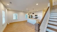 Located at 1821 W Mitchell St in Fayetteville, Arkansas, this well-appointed two-story home offers 3 bedrooms and 4 bathrooms across two thoughtfully designed floors. The main level features an open-concept kitchen and living room bathed in natural light from multiple windows fitted with slatted blinds. The kitchen stands out with crisp white shaker cabinetry, quartz countertops, a large center island with a pendant light and undermount sink, and a full suite of stainless steel appliances including a French door refrigerator, range, and built-in microwave. Light luxury vinyl plank flooring flows consistently throughout both levels, complementing the neutral, light gray walls. The living room is spacious and bright, anchored by a wood-railed staircase leading to the upper floor. The bedrooms are generously sized, each featuring ceiling fans with lighting, ample natural light, and closet space. The primary bedroom offers a notably comfortable footprint. Bathrooms are finished with quartz vanities, white cabinetry, and tub-shower combinations with brushed nickel fixtures. A dedicated laundry room houses a full-size washer and dryer. Clean, modern finishes and abundant natural light define the overall ambiance of this move-in ready home.