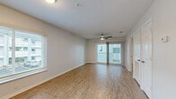This thoughtfully laid-out 1-bedroom, 1-bathroom residence spans a single floor and offers a clean, modern aesthetic throughout. The living room serves as the heart of the home, featuring warm wood-look flooring, a ceiling fan with light fixture, a sliding glass door leading to an outdoor balcony, and a side window fitted with horizontal blinds that invite natural light. The neutral color palette and textured ceiling contribute to a bright and welcoming ambiance.

The kitchen is efficiently designed with white shaker-style cabinetry, light countertops, a stainless steel range with overhead ventilation, and a full-size refrigerator, providing ample functionality in a compact layout.

The bedroom is a comfortable, well-proportioned retreat with wood-look flooring, a ceiling fan, and a window with outdoor views, offering a calm and restful environment. Built-in closet storage adds to the room's practicality.

The bathroom is neatly appointed with a single-sink vanity featuring white cabinetry, a combination tub and shower, and brushed nickel fixtures throughout. A dedicated in-unit laundry room accommodates a full-size washer and dryer side by side, adding significant everyday convenience. Clean lines and consistent finishes unify the space throughout.
