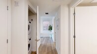 Located at 738 S Normandie Ave in Los Angeles' Koreatown neighborhood, this thoughtfully designed one-bedroom, one-bathroom unit makes excellent use of its compact footprint across a single floor. The open living and dining area serves as the heart of the home, featuring light wood flooring, crisp white walls, and multiple windows that flood the space with natural light and offer views of the surrounding cityscape. The living area comfortably accommodates a sofa, coffee table, and media console, creating a functional and inviting atmosphere.

A hallway connects the main living area to the private quarters, housing a dedicated in-unit laundry closet with a stacked washer and dryer — a practical convenience rarely found in similarly sized homes. The bedroom is a quiet, well-proportioned retreat with a sliding-door closet for organized storage, continuing the clean, minimal aesthetic found throughout.

The bathroom features striking black-and-white hexagonal tile flooring paired with a marble-surround tub and shower combination with matte black fixtures, adding a stylish contrast to the otherwise neutral palette. Throughout the unit, consistent light wood flooring and a bright, white finish create a cohesive, modern feel that maximizes the sense of openness and airiness.