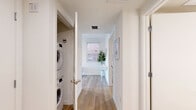 Located at 738 S Normandie Ave in Los Angeles' Koreatown neighborhood, this thoughtfully designed one-bedroom, one-bathroom unit makes excellent use of its compact footprint across a single floor. The open living and dining area serves as the heart of the home, featuring light wood flooring, crisp white walls, and multiple windows that flood the space with natural light and offer views of the surrounding cityscape. The living area comfortably accommodates a sofa, coffee table, and media console, creating a functional and inviting atmosphere.

A hallway connects the main living area to the private quarters, housing a dedicated in-unit laundry closet with a stacked washer and dryer — a practical convenience rarely found in similarly sized homes. The bedroom is a quiet, well-proportioned retreat with a sliding-door closet for organized storage, continuing the clean, minimal aesthetic found throughout.

The bathroom features striking black-and-white hexagonal tile flooring paired with a marble-surround tub and shower combination with matte black fixtures, adding a stylish contrast to the otherwise neutral palette. Throughout the unit, consistent light wood flooring and a bright, white finish create a cohesive, modern feel that maximizes the sense of openness and airiness.