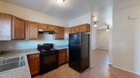 This single-floor residence offers a practical and comfortable layout designed for everyday living. The kitchen serves as a functional centerpiece, outfitted with warm honey-toned cabinetry, granite-style countertops, and a full suite of black appliances including an electric range, refrigerator, and dishwasher. Durable tile-style flooring runs throughout the kitchen, providing easy maintenance and a cohesive look. A double-basin sink beneath a window allows for natural light while completing daily tasks.

The living areas feature tile-style flooring and are fitted with ceiling fans, promoting airflow and comfort. The open flow between the living space and kitchen creates a connected, functional common area. The bedrooms are carpeted for warmth and comfort, each offering generous closet space with sliding or hinged doors. The primary bedroom includes direct access to an en-suite bathroom, adding convenience and privacy.

The bathrooms are clean and well-maintained, each featuring a full soaking tub and shower combination with built-in shelving, chrome fixtures, and a crisp white surround. Neutral wall tones throughout the home create a calm, versatile backdrop suitable for a variety of interior styles. Overall, this residence offers a straightforward, move-in-ready layout with practical finishes and well-organized spaces.