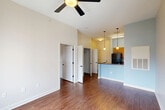 Located on Martin Luther King Jr. Boulevard in New Orleans, Louisiana, this one-bedroom residence offers a well-organized, efficiently designed layout with hardwood-style flooring throughout. The open living area is bright and airy, featuring a ceiling fan and clean neutral walls that create a welcoming atmosphere. The kitchen is a standout feature, showcasing warm honey-toned wood cabinetry, dark countertops, and black appliances including a range, refrigerator, and dishwasher. A full-height pantry cabinet provides generous storage, while the peninsula with pendant lighting above separates the kitchen from the living area, enhancing the open-concept feel. Natural light filters into the space through windows fitted with roller shades, offering views of the surrounding New Orleans neighborhood. The bedroom is a comfortable, private retreat with its own ceiling fan, a closet, and hardwood-style flooring consistent with the rest of the unit. Multiple interior doors provide access to additional storage and connecting spaces. The overall design is practical and clean, with light blue accent walls in the kitchen area adding a subtle pop of color to the otherwise neutral palette.