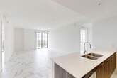 Located at 101 E Camino Real in the heart of Boca Raton, Florida, this thoughtfully designed single-floor residence offers three bedrooms and three bathrooms across a well-appointed layout. Consistent marble-look porcelain tile flows throughout every room, lending a clean, upscale aesthetic to the entire space.

The open-concept kitchen is a standout feature, anchored by a large island with a double undermount sink and crisp quartz countertops. Dark wood cabinetry contrasts beautifully with light upper cabinets, while stainless steel appliances and track lighting complete the modern culinary space. The kitchen flows seamlessly into the combined dining and living area, which is bathed in natural light from floor-to-ceiling windows and a sliding glass door opening onto a private balcony with outdoor views.

The primary bedroom is generously sized and accesses a balcony, while all bedrooms feature the same marble-look tile and ample closet space, including walk-in closets with built-in wire shelving. Three well-appointed bathrooms maintain the home's cohesive design, featuring wood-toned vanities with white quartz countertops, undermount sinks, chrome fixtures, and marble-tiled tub-shower combinations. A dedicated laundry area and multiple hallways provide practical convenience throughout this bright, modern Boca Raton residence.
