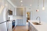 Located in La Plata, MD, this well-appointed 3-bedroom, 3-bathroom residence offers a thoughtfully designed single-floor layout that balances comfort and functionality. The entrance welcomes you into a bright, open-concept living, dining, and kitchen area finished with light hardwood-style flooring that flows seamlessly throughout the main spaces. The kitchen is a standout feature, showcasing gray shaker-style cabinetry reaching to the ceiling, white quartz countertops, a classic subway tile backsplash, stainless steel appliances including a refrigerator, range, and microwave, plus a large island with an undermount sink and elegant pendant lighting. The living area is filled with natural light from oversized windows and is accented by a ceiling fan. The spacious primary bedroom offers sweeping outdoor views through large corner windows, plush carpeting, and a generous walk-in closet with built-in wire shelving. The two additional bedrooms are carpeted and well-lit, each with ceiling fans and ample closet access. All three bathrooms feature gray vanities with white countertops and wood-look tile flooring. A dedicated in-unit laundry room with side-by-side washer and dryer adds everyday convenience. Four closets throughout provide excellent storage capacity.