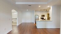 This well-appointed 2-bedroom, 2-bathroom residence in Suwanee, Georgia offers a thoughtfully designed single-floor layout with refined architectural details throughout. The open-concept living and kitchen area serves as the heart of the home, showcasing rich hardwood flooring, a tray ceiling with a ceiling fan, and a glass door flanked by large windows that invite abundant natural light and outdoor views. The kitchen is outfitted with white shaker cabinetry, granite countertops, stainless steel appliances including a refrigerator, range, and microwave, a tiled backsplash, and a central island with a sink. Elegant arched hallways with built-in shelving connect the living spaces to the private quarters, adding a distinctive architectural charm. The spacious primary bedroom features a tray ceiling and its own ceiling fan, while the secondary bedroom offers plush carpeting, a ceiling fan, and a large window with outdoor views. Both bathrooms are finished with granite vanities and white cabinetry, with one featuring a full tub-shower combination and tile flooring. A dedicated laundry room includes a full-size washer and dryer. Three closets and two hallways provide ample storage throughout this well-designed home.