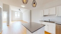 Located at 622 Main St in downtown Buffalo, NY, this well-appointed one-bedroom, one-bathroom unit offers a thoughtfully designed open floor plan with warm hardwood flooring throughout. The combined kitchen and living area serves as the heart of the space, featuring a central island with a gray quartz-style countertop, crisp white cabinetry, subway tile backsplash, and a full suite of stainless steel appliances including a range, microwave, dishwasher, and refrigerator. Stylish geometric pendant lights hang above the island, adding a contemporary touch. The living area flows naturally from the kitchen and is brightened by a large window and accented with a ceiling fan. The bedroom is a well-sized, sun-filled retreat with a ceiling fan, a window offering city views, and direct access to a spacious walk-in closet outfitted with wire shelving and hanging rods. The bathroom features large-format neutral tile flooring, a soaking tub with shower, a white vanity with gray countertop, and recessed lighting. Clean white walls and abundant natural light give the entire unit a bright, modern ambiance throughout.