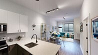 Located at 9 Presidential Blvd in Bala Cynwyd, PA, this well-appointed one-bedroom, one-bathroom residence offers a thoughtfully designed layout across a single floor. The open-concept kitchen and living area serves as the heart of the home, featuring a striking quartz waterfall island with an undermount sink, two-tone cabinetry with crisp white uppers and dark lower cabinets, stainless steel appliances, and pendant lighting that adds a contemporary touch. High ceilings amplify the sense of space, while wood-style flooring flows throughout the main living areas. The living room is bathed in natural light from large windows dressed with sheer curtains, creating a bright and welcoming atmosphere. The bedroom offers a serene retreat, highlighted by a bold accent wall, generous natural light from oversized windows, plush carpeting, and direct access to a walk-in closet. A second closet provides additional storage convenience. The bathroom features a sleek vanity with dark cabinetry, a full tub-shower combination with sliding glass doors, and wood-look tile flooring. A dedicated pantry rounds out the practical storage options in this efficiently designed residence.