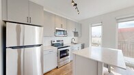 Located at 2703 Girard Ave S in Minneapolis, Minnesota, this thoughtfully designed one-bedroom, one-bathroom unit offers a clean, contemporary aesthetic throughout. Warm hardwood flooring flows consistently across the entire space, creating a cohesive and inviting atmosphere.

The kitchen is a standout feature, showcasing grey flat-front cabinetry with matte black hardware, a herringbone-patterned white tile backsplash, and quartz countertops. A central island provides additional prep and dining space, while a full suite of stainless steel appliances — including a refrigerator, electric range, over-the-range microwave, and dishwasher — adds both function and style. Track lighting overhead and a large window flood the kitchen with natural light.

The bedroom is a bright, comfortable retreat with a large window framing views of the surrounding neighborhood. A dedicated walk-in closet offers generous storage space, with matte black hardware accents maintaining design continuity.

The bathroom is finished with the same refined palette, featuring grey cabinetry, a marble-look quartz vanity top, a large mirror, matte black fixtures, and a full tub-shower combination. A soft blue accent wall adds a subtle touch of warmth and character. This unit presents a polished, move-in-ready living space in a modern Minneapolis setting.
