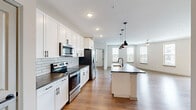 This well-appointed two-story residence at 500 Congaree Rd in Greenville, SC offers three bedrooms and three bathrooms spread across two evenly sized floors. The open-concept main level showcases a modern kitchen equipped with stainless steel appliances, white shaker cabinetry, a classic subway tile backsplash, dark countertops, and a large center island with pendant lighting — all flowing seamlessly into a bright living area lined with multiple windows and a ceiling fan. Wood-style flooring runs throughout the main living spaces, adding warmth and continuity. The bathrooms are tastefully finished with white subway tile, dark matte fixtures, white vanity cabinetry, and dark stone countertops; one features a walk-in glass shower while another offers a full soaking tub. The spacious primary bedroom includes plush carpeting, a ceiling fan, and access to a generous walk-in closet with built-in wire shelving. Additional bedrooms feature wood-style flooring and ample natural light, with one offering direct access to a private balcony with outdoor views. Two closets and a hallway provide practical storage throughout. The overall aesthetic is clean, contemporary, and move-in ready.