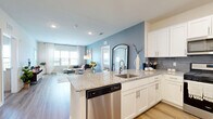 Located at 100 Aviv Street in Fogelsville, PA, this well-appointed 2-bedroom, 3-bathroom residence offers a thoughtfully designed single-floor layout. The open-concept kitchen and living area serves as the heart of the home, featuring crisp white shaker cabinets, a gray tile backsplash, granite countertops, and a full suite of stainless steel appliances including a refrigerator, gas range, microwave, and dishwasher. A central island with bar seating provides additional prep space and casual dining, while hardwood-style flooring flows throughout the main living areas. The living room is bright and inviting, benefiting from large windows dressed with sheer curtains that allow abundant natural light and offer outdoor views. A striking blue accent wall adds a pop of color and visual depth to the space. The spacious primary bedroom features plush carpeting, a ceiling fan, soft sage-colored accent wall, and large windows. The second bedroom is equally comfortable with warm neutral tones and natural light. Three well-finished bathrooms complete the layout, each featuring light tile flooring, white vanities, and clean, modern fixtures. Two dedicated closets provide ample storage throughout the home.