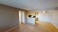 Located at 7002 W Indian School Rd in Phoenix, Arizona, this single-floor unit offers a practical and straightforward layout designed for comfortable everyday living. The entry opens into a well-proportioned living area finished with light wood-look flooring and neutral warm-toned walls, providing a clean, versatile canvas. A ceiling fan is positioned overhead, and a window fitted with vertical blinds allows natural light to filter in from the exterior.

The galley-style kitchen is thoughtfully arranged with light wood cabinetry lining both sides, offering generous storage and counter space. White laminate countertops complement the cabinetry, while a double stainless steel sink, black electric range, black refrigerator, and built-in microwave provide a complete set of appliances. A recessed skylight panel above the kitchen enhances brightness throughout the cooking area.

The bedrooms are carpeted for comfort, featuring neutral toned walls and windows with vertical blinds that bring in natural light. The textured ceilings carry consistently throughout the unit, adding a subtle architectural detail to each room.

The bathroom includes a full tub and shower combination with a curtain rod, a toilet, wood-look tile flooring, and a vanity with a light countertop. The overall layout, as seen from the dollhouse view, is efficiently organized with clearly defined living, sleeping, and kitchen zones.
