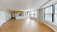 Located in Chicago's vibrant Old Town neighborhood, this single-floor residence at 1536 N Cleveland Ave offers a well-designed, open-concept layout finished with warm hardwood flooring throughout. The expansive living area is defined by a gracefully curved wall of large windows that flood the space with natural light and frame views of the surrounding neighborhood, creating a bright and airy atmosphere.

The kitchen is seamlessly integrated into the living space and features warm wood cabinetry, stainless steel appliances including a gas range, built-in microwave, and refrigerator, along with a generous granite-topped island that doubles as a breakfast bar. Pendant lighting accents the kitchen, adding a modern touch.

The bedrooms are well-proportioned, each featuring hardwood flooring, neutral wall tones, and individual windows that bring in additional natural light. One bedroom offers a city skyline view, while another features a private access door. The bathrooms are finished with granite-topped vanities, warm wood cabinetry, and tub-shower combinations, maintaining a consistent, polished aesthetic throughout. Clean lines, neutral tones, and quality finishes define the overall ambiance of this inviting urban residence.