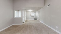 Located at 19606 Park Row Dr in Houston, TX, this single-story, 2-bedroom, 2-bathroom unit offers a well-organized layout with a hallway connecting all rooms. The open living area is a standout feature, showcasing a white brick wood-burning fireplace flanked by built-in shelving, a ceiling fan with light fixture, and a sliding glass door that allows natural light and outdoor views. Neutral-toned carpet flows throughout the living area and bedrooms, complementing the light gray walls.

The galley-style kitchen is equipped with white cabinetry featuring brushed nickel hardware, light countertops, a double-basin stainless steel sink, and black appliances including a range, refrigerator, and dishwasher. Wood-look vinyl flooring runs through the kitchen and bathrooms.

Both bedrooms feature carpet, textured ceilings, and ample natural light from windows with blinds. The primary bedroom includes a walk-in closet with built-in shelving and hanging rods. Both bathrooms offer white vanities with light countertops, mirrors, and tub-shower combinations with tile surrounds.