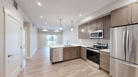 Located at 111 W Lamme Street in the heart of Bozeman, Montana, this well-appointed one-bedroom, one-bathroom unit offers a thoughtfully designed layout with modern finishes throughout. The open-concept living and kitchen area serves as the centerpiece of the unit, featuring light wood-look flooring, recessed lighting, and a sliding glass door that fills the space with natural light and provides access to an outdoor balcony. The kitchen is outfitted with taupe flat-panel cabinetry, crisp white countertops with a peninsula overhang, stainless steel appliances including a refrigerator, range, microwave, and dishwasher, and stylish pendant lighting above the peninsula. A subway tile backsplash adds a clean, contemporary touch. The bedroom offers a comfortable footprint with plush carpet flooring, recessed lighting, and two windows that bring in natural light. A sliding closet door provides convenient storage. The bathroom is finished with a frameless glass walk-in shower featuring white tile surround, a built-in bench, and brushed nickel fixtures, complemented by wood-look tile flooring. A hallway connects the spaces efficiently, completing this modern and functional Bozeman residence.