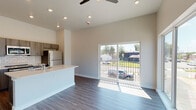 This single-story unit in Memphis, TN offers a thoughtfully designed open-concept layout that maximizes its efficient footprint. The living area features dark wood-style flooring, recessed lighting, and a ceiling fan, creating a comfortable and contemporary atmosphere. A large sliding glass door floods the space with natural light while providing direct views of the surrounding neighborhood, and additional oversized windows along the living area walls further enhance the bright, airy feel.

The kitchen is a standout feature, centered around a spacious island with a white quartz countertop and double undermount sink. Dark wood cabinetry, a white subway tile backsplash, and stainless steel appliances — including a refrigerator, range, and built-in microwave — give the kitchen a modern, functional character that opens seamlessly to the living space.

The bathroom is finished with large-format marble-look tile on both the floor and tub surround, paired with a clean white quartz vanity top and wood-toned cabinetry, lending a polished, upscale aesthetic. A hallway connects the bedroom, bathroom, and living areas, completing this well-organized and move-in-ready single-level home.