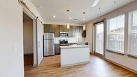 Located on Cheshire Bridge Road in Atlanta, GA, this one-bedroom, one-bathroom unit offers a well-designed layout with modern finishes throughout. Light wood-style flooring flows continuously across the entire space, lending a clean and cohesive aesthetic.

The kitchen is a standout feature, equipped with stainless steel appliances including a refrigerator, range, microwave, and dishwasher. Gray shaker-style cabinetry pairs with granite countertops and a white subway tile backsplash, while a central island provides additional prep space and pendant lighting adds a contemporary touch. A sliding barn door and large windows allow natural light to fill the open living area.

A hallway connects the main living space to the bedroom, which is a comfortable, well-proportioned room with a ceiling fan and wood-style flooring. Two closets provide generous storage. The bathroom features a full soaking tub and shower combination with classic white subway tile surround and wood-look flooring. An in-unit laundry area adds everyday convenience.

A private balcony extends the living space outdoors. The unit's crisp white walls, recessed lighting, and modern hardware throughout create a bright, move-in-ready environment ideal for those seeking functional urban living in Atlanta.