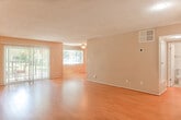 Located at 5140 White Oak Ave in the Encino neighborhood of Los Angeles, this single-floor residence offers a thoughtfully laid-out interior finished with consistent warm-toned wood-look flooring throughout the living areas and bedroom. The spacious living room is bathed in natural light, courtesy of large windows and a sliding glass door fitted with vertical blinds that opens to an outdoor space, creating a seamless indoor-outdoor connection. A textured popcorn ceiling adds a classic character to the open living area. The galley-style kitchen is well-appointed with rich wood cabinetry, granite countertops, a stainless steel double sink, and black appliances including a range, microwave, and refrigerator, all set atop light tile flooring. The generously sized bedroom provides ample storage with two sets of double closets spanning an entire wall. The bathroom continues the granite theme with a warm-toned stone vanity countertop, rich wood cabinetry with ample drawer storage, and a large mirror that enhances the sense of space. Throughout the unit, neutral wall tones and consistent finishes create a cohesive and inviting atmosphere suited for comfortable everyday living.