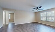 Located at Turtle Creek Drive in Naples, Florida, this three-bedroom, two-bathroom single-floor residence offers a practical and well-appointed layout across a comfortable footprint. The living room serves as the heart of the home, featuring wood-look laminate flooring, neutral beige walls, and a ceiling fan that enhances airflow — with a large window that invites natural light and views of the lush Florida landscaping outside.

The kitchen is designed for functionality and style, featuring crisp white cabinetry, granite-look countertops, a subway tile backsplash, and a full suite of stainless steel appliances including a refrigerator, range, and microwave. A peninsula counter provides additional prep space and connects the kitchen to the main living area in an open layout. A dedicated laundry room adjacent to the kitchen houses a full-size washer and dryer alongside wire shelving for added storage.

The three bedrooms are carpeted for comfort, each featuring louvered bi-fold closet doors and ceiling fans. The secondary bedrooms benefit from natural light through windows framing views of tropical palm foliage. Both bathrooms are finished with granite-top white vanities and full tub-shower combinations with clean white tile surrounds and wood-look flooring, completing this well-maintained Naples residence.