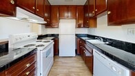 This one-bedroom, one-bathroom residence in Sacramento, CA offers a well-organized single-floor layout designed for comfortable everyday living. The open-concept kitchen and living area forms the heart of the home, where rich mahogany-toned cabinetry extends from floor to ceiling, providing generous storage. Dark tile countertops contrast neatly against white appliances, including a range, refrigerator, and dishwasher. A peninsula with an extended countertop creates a natural division between the kitchen and living area, doubling as a casual dining or workspace. The living area features soft carpeting and a textured ceiling, with a sliding glass door that opens to a private balcony overlooking a tree-lined outdoor setting, filling the space with natural light. The bedroom is a comfortable retreat with plush carpet, a dedicated closet featuring built-in shelving and a hanging rod, and access to additional closet storage throughout the unit — four closets in total provide exceptional organizational capacity. The bathroom includes a clean, tile-surround shower and wood-look flooring. A connecting hallway links all areas efficiently. The overall ambiance is practical and classic, well-suited for those seeking functional living in Sacramento's 95831 neighborhood.