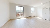 Located at 1 Slessor Blvd in Grimsby, Ontario, this thoughtfully designed 2-bedroom, 1-bathroom unit offers a clean, contemporary aesthetic throughout. Light-toned hardwood flooring runs continuously across the living spaces, complementing the bright white walls and creating a cohesive, airy atmosphere.

The open-concept living room and kitchen area is bathed in natural light, with a large sliding glass door leading to a private balcony that frames picturesque views of the surrounding hillside and greenery. The kitchen is well-appointed with sleek white cabinetry extending to the ceiling, a light grey countertop with a breakfast bar peninsula, and a full suite of stainless steel appliances including a refrigerator, range, microwave, and dishwasher.

The primary bedroom is a generous, sun-filled space featuring a sliding glass door to the balcony, offering the same scenic outdoor views and abundant natural light. The second bedroom is equally bright, with a large window overlooking the landscape, light hardwood floors, and a built-in sliding door closet providing practical storage. Both bedrooms are serviced by a full bathroom finished with large-format tile flooring and a full tub-shower combination with white tile surround.