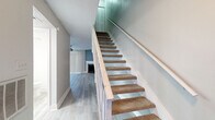 This two-story home offers a thoughtfully arranged layout with three bedrooms and three bathrooms across two well-proportioned floors. The main level features an open living area anchored by a fireplace and ceiling fan, seamlessly connected to a galley-style kitchen. The kitchen is outfitted with white shaker cabinetry, granite countertops, a subway tile backsplash, stainless steel appliances, and a peninsula with pendant lighting — all complemented by light wood-style flooring that runs throughout the home. A bay window nook adjacent to the kitchen adds a charming architectural detail and brings in natural light. The bathrooms feature granite-topped vanities with white cabinetry, maintaining a clean and cohesive aesthetic. A carpeted staircase with white wood railings connects the two floors, leading to the upper level where the bedrooms are located. The spacious primary bedroom offers comfortable proportions, while the additional bedrooms are well-sized and bright, each with ceiling fans and large windows. Textured ceilings are present throughout, and the neutral color palette of warm greiges and soft grays gives the entire home a clean, move-in-ready feel.