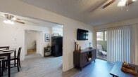 This single-floor residence offers a thoughtfully designed layout that balances functionality and comfort throughout its key living areas. The living room serves as the heart of the home, featuring wood-look flooring, a ceiling fan with light fixture, and a wall-mounted television setup. A sliding glass door floods the space with natural light and opens directly to a private balcony, providing a seamless indoor-outdoor connection. Adjacent to the living room, the dining area is a defined space with its own ceiling fan and easy access to the kitchen, making it ideal for everyday meals or entertaining. The galley-style kitchen is efficiently designed with white cabinetry, granite-look countertops, and a full suite of black appliances including a refrigerator, range, dishwasher, and over-the-range microwave. A window above the sink brings in additional natural light. The bedroom is a serene retreat, finished with plush carpeting, a ceiling fan, and a closet with built-in hanging space. Windows allow natural light to brighten the room. The bathroom is cleanly appointed with wood-look flooring, a vanity with countertop space, and a shower-tub combination. Throughout the residence, textured ceilings and neutral wall tones create a cohesive and welcoming atmosphere.