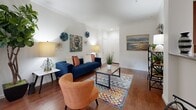 This single-story, 2-bedroom, 1-bathroom residence offers a smartly organized layout across a comfortable footprint. The open-plan living and dining area is anchored by rich hardwood-style flooring, crown molding, and a sliding glass door that floods the space with natural light and provides access to an outdoor area. The living room offers ample room for seating, while the adjacent dining area features a large window dressed with bold blue curtains, framing pleasant outdoor views.

The galley-style kitchen is well-equipped with warm wood cabinetry, granite-style countertops, a tile backsplash, and black appliances, offering efficient use of space with generous storage. The full bathroom features tile flooring, a tub-shower combination with diagonal-set tile surround, and a wood-vanity with a white basin.

The primary bedroom is a well-sized retreat with plush carpeting, a ceiling fan, and soft lighting. The second bedroom, also carpeted and ceiling fan-equipped, offers flexibility as a home office or guest room with a large window providing natural light. Three closets throughout the unit ensure excellent storage capacity. A dedicated laundry room houses a full-sized washer and dryer. The hallway connects all areas cohesively, completing this functional and comfortable floor plan.