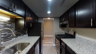 Located at 2745 Coldstream Ln in Columbus, Ohio, this single-floor residence offers a thoughtfully updated interior with a cohesive, modern aesthetic throughout. The layout flows naturally between distinct living areas, each finished with complementary materials and neutral warm tones.

The kitchen stands out as a highlight of the space, featuring dark espresso cabinetry lining both sides of a galley-style configuration. Light granite countertops provide a striking contrast against the rich cabinetry, while stainless steel appliances — including a gas range and refrigerator — complete the functional design. A tile backsplash adds texture, and recessed lighting keeps the space well-lit. The kitchen opens directly into the rest of the unit via a connecting hallway with wood-style flooring.

The living areas feature wood-style plank flooring in a natural tone, contributing warmth and visual continuity. Multiple windows allow natural light to filter in, offering views of the surrounding exterior. The bedroom areas are finished with plush carpet and neutral wall tones, with windows providing additional natural light and ventilation.

The bathroom includes a granite-topped vanity with white cabinetry, a tub-shower combination, and tile flooring, maintaining the updated aesthetic found throughout the rest of the unit.