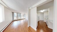 Located in the heart of Calgary, this 2-bedroom, 1-bathroom unit offers a well-organized layout designed for comfortable urban living. Warm hardwood flooring flows consistently throughout the space, creating a cohesive and inviting atmosphere from room to room.

The living room is a standout feature, anchored by a full wall of floor-to-ceiling sliding glass doors that open onto a private balcony. This expansive glazing floods the room with natural light and frames open city views, making it the social centerpiece of the unit. The adjacent dining area provides a seamless transition between living and kitchen spaces.

The galley-style kitchen is efficiently arranged, featuring white cabinetry, white appliances including a stove and refrigerator, and marble-look countertops that add a clean, contemporary touch. A dedicated entrance off the kitchen provides convenient access.

Both bedrooms are comfortably sized with hardwood floors, neutral walls, and large windows dressed with vertical blinds that allow natural light while maintaining privacy. The primary bedroom includes built-in sliding door closets, offering practical storage. 

The bathroom is finished with classic white subway tile surrounding a full soaker tub and shower combination, complemented by marble-look countertop detailing. Throughout the unit, a consistent white and neutral palette creates a bright, clean aesthetic well-suited to downtown Calgary living.
