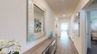 Located at 2771 Lust Rd in Apopka, Florida, this single-story home offers a cohesive, light-filled interior with a coastal-inspired aesthetic carried throughout. The entryway sets an inviting tone, featuring wood-look flooring that extends through the entire home, clean white walls, and a long hallway that leads to the main living spaces.

The kitchen serves as a central hub, outfitted with white cabinetry, a subway tile backsplash, stainless steel appliances, and a granite-topped island with seating for multiple guests. Recessed lighting illuminates the space effectively. Adjacent to the kitchen, the combined living and dining area benefits from multiple windows and a sliding glass door, filling the space with natural light and providing outdoor views. Ceiling fans are present in both the living room and bedroom areas.

The bedrooms are comfortably sized with ample natural light from well-positioned windows. Bathrooms feature granite countertops, white cabinetry with brushed nickel hardware, and wood-look flooring. One bathroom includes a walk-in shower, while another offers a full tub-shower combination. A dedicated laundry room accommodates a full-size washer and dryer. The overall ambiance is bright, clean, and well-organized throughout.