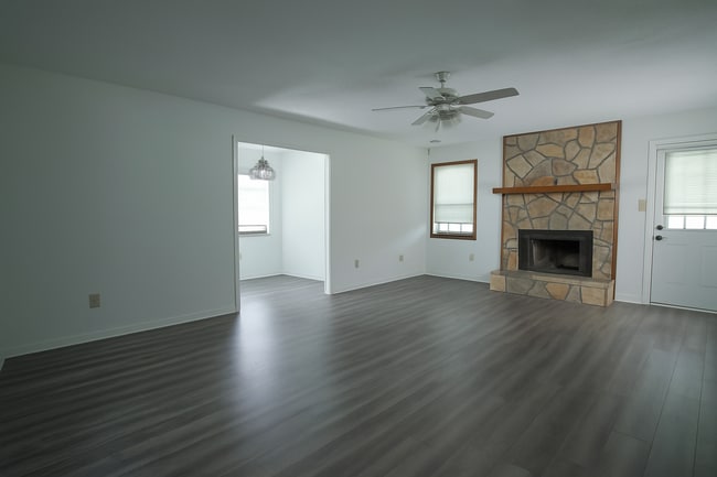 Open living space with stone fireplace, wood-look floors, and bright bonus room. - 2313 Salem West Dr