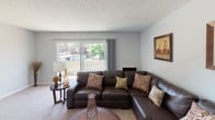 Located at 2101 California St in Mountain View, California, this single-floor residence offers a well-organized and comfortable layout designed for everyday living. The living room serves as the heart of the home, featuring soft carpeting, neutral gray walls, and a large sliding glass door that opens to a private balcony, allowing natural light to fill the space and providing pleasant views of surrounding greenery. A dedicated dining area with hardwood-style flooring sits adjacent, creating a natural flow between entertaining and meal spaces. The kitchen is efficiently designed with white cabinetry, stone-look countertops, and stainless steel appliances including a refrigerator, electric range, and over-the-range microwave. The bedrooms are carpeted and finished with soft gray walls, each featuring windows that bring in natural light and views of the tree-lined surroundings. Baseboard heating is present throughout, ensuring year-round comfort. The bathroom is clean and functional, equipped with a tub-shower combination enclosed by sliding glass doors and chrome fixtures. Textured ceilings are consistent throughout the residence, adding a classic touch to the overall aesthetic.