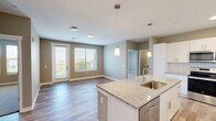 This well-appointed 2-bedroom, 2-bathroom residence in Birmingham, Alabama offers a thoughtfully designed single-level layout that balances comfort and functionality. The open-concept kitchen and living area serves as the heart of the home, featuring wood-look flooring, pendant lighting, and generous windows and a glass door that flood the space with natural light and provide outdoor views. The kitchen is outfitted with crisp white shaker cabinetry, granite countertops, a subway tile backsplash, a center island with a built-in sink, and stainless steel appliances including a range, microwave, and dishwasher. A dedicated pantry provides additional storage convenience. Both bedrooms are carpeted and feature ceiling fans and windows with outdoor views. The primary bedroom is a comfortable retreat with its own well-sized closet. Three closets in total offer ample storage throughout. The bathrooms feature granite-topped white vanities with undermount sinks and large mirrors. A utility room and additional storage areas round out the practical features of this efficiently arranged residence.