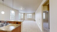 This single-floor, 3-bedroom, 1-bathroom residence offers a functional and comfortable layout designed to maximize the use of space. The open-concept living area is bright and welcoming, featuring plush wall-to-wall carpeting and multiple windows that fill the room with natural light and offer views of surrounding greenery. A peninsula with granite-style countertops connects the living area to the kitchen, creating a natural flow between the two spaces.

The kitchen is well-equipped with warm wood cabinetry, stainless steel appliances including a full-size refrigerator, range, and dishwasher, and light hardwood-style flooring. A window above the sink brings in additional natural light.

The primary bedroom is generously sized, featuring corner windows on two walls that flood the room with daylight and provide pleasant outdoor views. The additional bedrooms are carpeted and offer versatile spaces suitable for various uses. A dedicated closet and laundry area add everyday convenience to the layout.

The bathroom is neatly appointed with a wood-toned vanity, granite-style countertop, a large mirror, and a tub-shower combination. A central hallway connects all rooms, ensuring a practical and organized flow throughout the residence.