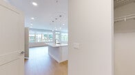 This well-appointed single-floor residence offers three bedrooms and three full bathrooms across a thoughtfully designed open layout. The combined kitchen and living room serves as the heart of the home, featuring a central island with pendant lighting, white shaker cabinetry extending to the ceiling, stainless steel appliances including a gas range, microwave, and refrigerator, and a neutral tile backsplash. Large windows in the living area flood the space with natural light and provide outdoor views, with direct access to an exterior balcony or patio through a glass door. Light wood-style flooring runs consistently throughout the main living areas and bedrooms, lending warmth and cohesion to the overall design. The bedrooms are generously sized, with the primary bedroom benefiting from a dedicated walk-in closet featuring built-in shelving and double hanging rods. The primary bathroom includes a dual-sink vanity with white cabinetry, a large mirror with overhead lighting, marble-style tile flooring, and a glass-enclosed shower. Two additional bedrooms offer ample space and natural light through wide windows with roller shades. A hallway connects the rooms efficiently, completing this clean, modern, and functional layout.