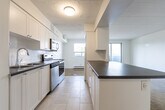Located at 110 Nonquon Rd in Oshawa, Ontario, this single-floor, 3-bedroom, 1-bathroom unit offers a functional and well-organized layout. Throughout the space, warm parquet hardwood flooring provides a classic, timeless aesthetic that complements the crisp white walls found in every room.

The entry foyer transitions seamlessly into the living and dining area, a combined space that offers room for both relaxing and entertaining. The kitchen is conveniently positioned nearby, providing a practical flow for daily living.

Each of the three bedrooms features the same parquet flooring and clean white walls, creating a bright, neutral environment. The bedrooms are served by wall-mounted light fixtures, and several rooms offer windows with views of surrounding mature trees, bringing in natural light and a pleasant outdoor connection. Baseboard heating is present throughout, ensuring comfort year-round.

The bathroom is finished in a clean, contemporary style with white subway tile surrounding the bathtub, a single-sink vanity with white cabinetry, tile flooring, and a bright vanity mirror with overhead lighting. Bold dark-paneled doors provide a stylish contrast to the light interior palette, adding a modern design touch to the overall space.