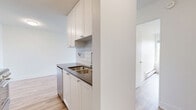 Located at 720 Queens Ave in New Westminster, BC, this well-appointed 2-bedroom, 1-bathroom unit offers a clean, modern aesthetic throughout its thoughtfully designed single-floor layout. Light-toned hardwood flooring runs seamlessly through every room, complementing the crisp white walls and creating a bright, cohesive ambiance.

The living room is a standout space, featuring a large sliding glass door that opens onto a private balcony overlooking lush tree canopies and open sky. A baseboard heating system lines the wall, ensuring year-round comfort. Natural light fills the room generously, enhancing the airy feel of the open layout that connects to the kitchen area.

The primary bedroom is a well-sized retreat featuring a window with pleasant outdoor views and a full-width mirrored sliding closet that adds depth and storage. The second bedroom is equally bright, with its own window and ample wall space, offering versatility as a guest room or home office.

The bathroom is finished with clean, neutral tones, featuring a speckled quartz-style vanity countertop and chrome fixtures, including a towel bar and modern hardware, lending a polished and functional finish.

Throughout the unit, the consistent use of light materials and neutral tones creates a calm, inviting atmosphere well-suited for comfortable everyday living.