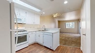 Located at 1530 W Avenue K-8 in Lancaster, California, this single-floor, 1-bedroom, 2-bathroom residence offers a thoughtfully designed layout that maximizes its compact footprint. The open-concept kitchen flows seamlessly into the combined dining and living area, creating a connected and functional common space. The kitchen is outfitted with white cabinetry, light-toned countertops, and a full suite of white appliances including a gas range, over-the-range microwave, dishwasher, and refrigerator. A skylight and recessed lighting brighten the kitchen, while a ceiling fan overhead serves the living area. Wood-look flooring runs throughout the kitchen and entrance, transitioning to plush carpet in the living and bedroom areas. The bedroom is a comfortable retreat featuring a window with outdoor views and generous closet access — three closets are distributed throughout the unit for ample storage. Two bathrooms include wood-look flooring, clean white finishes, and a tub-shower combination with grab bars. A private balcony extends the living space outdoors, and a dedicated entrance completes this well-appointed residence.