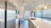 Located at Casella in Spring, TX, this single-floor, 3-bedroom, 2-bathroom home offers a thoughtfully designed layout with modern finishes throughout. The kitchen is a standout centerpiece, featuring stainless steel appliances including a French door refrigerator, over-the-range microwave, and range with oven, all complemented by crisp white quartz countertops, a large island with an undermount sink, soft gray shaker-style cabinetry, and a classic subway tile backsplash. Pendant lighting adds a refined touch overhead. The dining area benefits from large windows that invite generous natural light and is accented by an elegant chandelier, with wood-look flooring flowing throughout the main living areas. The spacious primary bedroom includes a ceiling fan and oversized windows, while the secondary bedrooms offer plush carpeting and ample natural light. The primary bathroom features a dual-sink vanity with quartz countertops, a framed mirror, and a glass-enclosed tiled shower. The secondary bathroom mirrors the same quality with a tiled tub-surround and wood-look flooring. A hallway and dedicated closet space round out this well-organized, move-in-ready home with a clean, contemporary aesthetic.