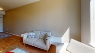 This single-floor residence offers a well-organized layout that balances functional living spaces with contemporary design. The kitchen is a standout area, equipped with stainless steel appliances including a refrigerator, electric range, and dishwasher. Warm-toned wood cabinetry pairs with light countertops, and a peninsula with bar seating provides a casual dining option. Hardwood-style flooring runs throughout the kitchen and entry, adding warmth to the space.

The living area features vaulted-style angled ceilings that lend an open, airy feel, complemented by neutral wall tones that create a calm, inviting atmosphere. The bedrooms are carpeted and bright, each benefiting from large windows that frame urban skyline views, with ceiling fans providing additional comfort. Natural light flows generously throughout.

Two bathrooms serve the residence, one featuring a full soaking tub with a shower rod and a wood-toned vanity, while the other doubles as a laundry room with a stacked washer and dryer unit conveniently integrated into the space. Both bathrooms feature neutral flooring and clean, white fixtures. Overall, the residence presents a cohesive, modern aesthetic well-suited to urban living.