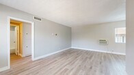 Located at 1311 N Azusa Ave in Azusa, California, this single-story unit offers a well-organized layout with one bedroom, three bathrooms, and a combined kitchen and living area. Light wood-style vinyl flooring runs throughout the entire unit, creating a clean and cohesive aesthetic complemented by soft neutral gray walls and crisp white baseboards.

The open living room receives natural light through a large window overlooking the exterior, with a wall-mounted AC unit providing climate control. A textured ceiling and a pass-through opening connect the living area to the kitchen, which features rich wood-toned upper and lower cabinetry, dark granite-style countertops, stainless steel appliances including a gas range and refrigerator, and a ventilation hood — making it both functional and visually appealing.

The bedroom is a comfortable, private retreat with a ceiling fan, a sliding closet, and a window that brings in natural daylight. The three bathrooms are each finished with white vanity cabinetry, brushed nickel hardware, mirrored medicine cabinets, and light wood-style flooring. At least one bathroom includes a full tub-shower combo with clean white tile surround. A hallway connects the rooms, offering an efficient and practical flow throughout the unit.