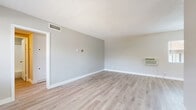 Located at 1311 N Azusa Ave in Azusa, California, this single-story unit offers a well-organized layout with one bedroom, three bathrooms, and a combined kitchen and living area. Light wood-style vinyl flooring runs throughout the entire unit, creating a clean and cohesive aesthetic complemented by soft neutral gray walls and crisp white baseboards.

The open living room receives natural light through a large window overlooking the exterior, with a wall-mounted AC unit providing climate control. A textured ceiling and a pass-through opening connect the living area to the kitchen, which features rich wood-toned upper and lower cabinetry, dark granite-style countertops, stainless steel appliances including a gas range and refrigerator, and a ventilation hood — making it both functional and visually appealing.

The bedroom is a comfortable, private retreat with a ceiling fan, a sliding closet, and a window that brings in natural daylight. The three bathrooms are each finished with white vanity cabinetry, brushed nickel hardware, mirrored medicine cabinets, and light wood-style flooring. At least one bathroom includes a full tub-shower combo with clean white tile surround. A hallway connects the rooms, offering an efficient and practical flow throughout the unit.