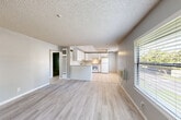 Located at 7323 College View Dr in Rohnert Park, CA, this two-bedroom, one-bathroom single-floor home offers a practical and comfortable layout. The open-concept main area seamlessly combines the living room, dining space, and kitchen into one cohesive zone. Light gray walls and light-toned laminate wood flooring run throughout the living spaces, creating a clean, neutral palette. The kitchen features white cabinetry, a gas range, a full-size refrigerator, a ceiling fan overhead, and light tile flooring, with a peninsula that separates it from the dining and living areas. Natural light filters in through windows fitted with horizontal blinds, offering outdoor views of surrounding greenery. The primary bedroom provides a comfortable footprint with a mirrored sliding closet door and its own window. The second bedroom also includes laminate flooring, a window with natural light, and access to ample closet space. The home includes four closets in total, distributed throughout. A hallway connects the bedrooms to the full bathroom, which is finished with white tile flooring, a tub-shower combination, and a white vanity. Textured ceilings are present throughout, adding a classic architectural detail to this well-organized and functional home.