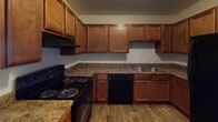 Located at 1100 Barbara Ann Cir in Winston-Salem, NC, this single-story home offers a practical and comfortable layout throughout. The kitchen is a functional centerpiece, featuring rich warm-toned wood cabinetry extending to the upper walls for generous storage, dark granite-style countertops, wood-look flooring, and black appliances including an electric range, dishwasher, and double-basin sink — all complemented by a textured ceiling overhead. The bedrooms are carpeted in neutral tones, providing a cozy feel, and are brightened by windows that allow natural light to filter in. The rooms are well-proportioned with clean white walls and straightforward ceiling fixtures, offering a versatile canvas for various arrangements. A hallway connects the living areas to the bedrooms and bathroom, with closet access visible along the corridor. The full bathroom includes a single-sink vanity with warm wood cabinetry, a white countertop, a combination tub and shower unit, and wood-look flooring that ties cohesively to the rest of the home. Overall, the space presents a clean, move-in-ready environment with consistent finishes throughout its single floor.