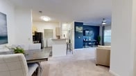 Located at 4402 River Birch Loop in High Point, NC, this single-floor, 2-bedroom, 1-bathroom residence offers a thoughtfully designed open-concept layout that maximizes functionality and flow. The living room serves as a central gathering space, featuring plush carpeting, a bold navy accent wall, large windows that invite natural light, and a ceiling fan overhead. The kitchen is equipped with light wood cabinetry, black appliances including a refrigerator and range, granite-style countertops, and a breakfast bar with bar seating — all seamlessly connected to the dining and living areas. A dedicated laundry area with full-size washer and dryer units adds everyday convenience. Both bedrooms are carpeted and feature soft blue accent walls, natural light from well-placed windows, and ample closet space. The primary bedroom is generously sized, providing a comfortable retreat. The bathroom includes a full tub-shower combination, wood-look flooring, a wide vanity with light wood cabinetry, and a large mirror. Additional storage is provided through two closets and a hallway. The residence maintains a consistent, calming aesthetic throughout, blending warm neutrals with cool blue tones for a cohesive and inviting atmosphere.
