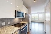 Located at 455 S Maple Ave in Falls Church, Virginia, this well-appointed one-bedroom, one-bathroom residence offers a thoughtfully designed layout across a single floor. The kitchen is outfitted with stainless steel appliances including a electric range, over-the-range microwave, French door refrigerator, and dishwasher. Granite countertops, a subway tile backsplash, and crisp white upper cabinetry with modern hardware complement the warm wood-tone lower cabinetry, creating a clean, contemporary aesthetic. Hardwood-style flooring extends through the kitchen and into the open-concept dining and living area, which benefits from a large window that fills the space with natural light and offers views of the surrounding neighborhood. A stacked washer and dryer is conveniently integrated near the kitchen, adding in-unit laundry functionality. The bedroom features soft carpeting, bright white walls, and two windows that invite ample daylight and outdoor views. Two closets provide generous storage throughout the unit. The bathroom is finished with large-format white tile flooring, a tub-shower combination with grey subway tile surround, dark espresso cabinetry, and granite countertops, delivering a refined and cohesive look throughout the home.