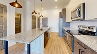 Located at 7 Vance Avenue in Memphis, TN, this well-appointed one-bedroom, one-bathroom residence offers a thoughtfully designed layout with modern finishes throughout. Light-toned hardwood-style flooring flows seamlessly across the entire space, complementing the bright, neutral color palette and clean architectural lines.

The open-concept kitchen and living area serves as the heart of the home. The kitchen is outfitted with a large granite-topped island featuring an undermount sink, two-tone cabinetry in dark wood and white, stainless steel appliances including a side-by-side refrigerator, electric range, and microwave, and stylish pendant lighting overhead. The adjacent living area provides an open, flexible space ideal for everyday living.

The bedroom is a comfortable retreat, featuring a ceiling fan, large windows that invite natural light and outdoor views, and a set of glass-paned French doors leading to a private exterior access point. Distinctive gray five-panel doors lend the room a modern, sophisticated character.

The bathroom is finished with a granite-topped vanity with gray cabinetry, black hardware accents, and a glass-enclosed walk-in shower with tile surround. A spacious walk-in closet with wire shelving systems provides generous storage. Recessed lighting and pendant fixtures complete this polished, contemporary residence.