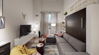 This compact yet cleverly designed single-floor space maximizes every square foot through thoughtful layout and eclectic, colorful décor. The main living area serves a dual purpose, featuring a Murphy bed integrated into a dark wood wall unit with built-in shelving, allowing the space to transition seamlessly between a living room and sleeping area. Soaring ceilings amplify the sense of openness, while a tall, narrow window dressed in patterned geometric curtains draws in natural light and offers outward views. A sectional sofa, layered area rug, and an assortment of accent pieces contribute to the room's lively, personalized character.

The kitchen is efficiently arranged with dark espresso cabinetry, granite-look countertops, and a linear mosaic tile backsplash. A full-size stainless steel refrigerator, over-the-range microwave, and open shelving for display and storage complete the functional cooking space. Track lighting illuminates the area with precision.

The bathroom makes a bold statement with wide horizontal blue and white stripes adorning the walls, accented by a black-and-white checkered tile border above the tub. A shower-tub combo with a chrome rain showerhead rounds out this eye-catching space.